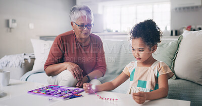 Buy stock photo Activity, fun or jewellery making with girl and grandmother in living room of home for bonding or crafts. Creative, diy or necklace with grandchild and senior woman in apartment for relationship