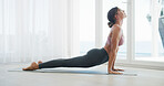 Woman, home and cobra pose with stretching for exercise, yoga and body health by window at house. Female person, wellness and yogi posture for self care, fitness with zen or relief in apartment