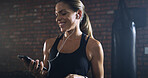 Woman, earphones and phone at gym with smile, music or mobile app for social network at fitness club. Person, audio and streaming subscription with smartphone, exercise and happy with chat on web