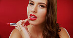 Portrait, woman and lipstick for beauty in studio with makeup, facial makeover and foundation glow. Female person, touch and cosmetics with bold glamour, lip color and check results on red background