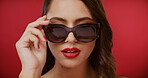 Beauty, sunglasses and face of woman in studio for fashion, trendy style and cosmetics. Space, designer aesthetic and confident person with accessories, makeup and red lipstick on color background