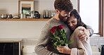 Flowers, hug and romance with couple in living room of home together for anniversary celebration. Bouquet of roses, gift or love with man and woman embracing in apartment for bonding or security