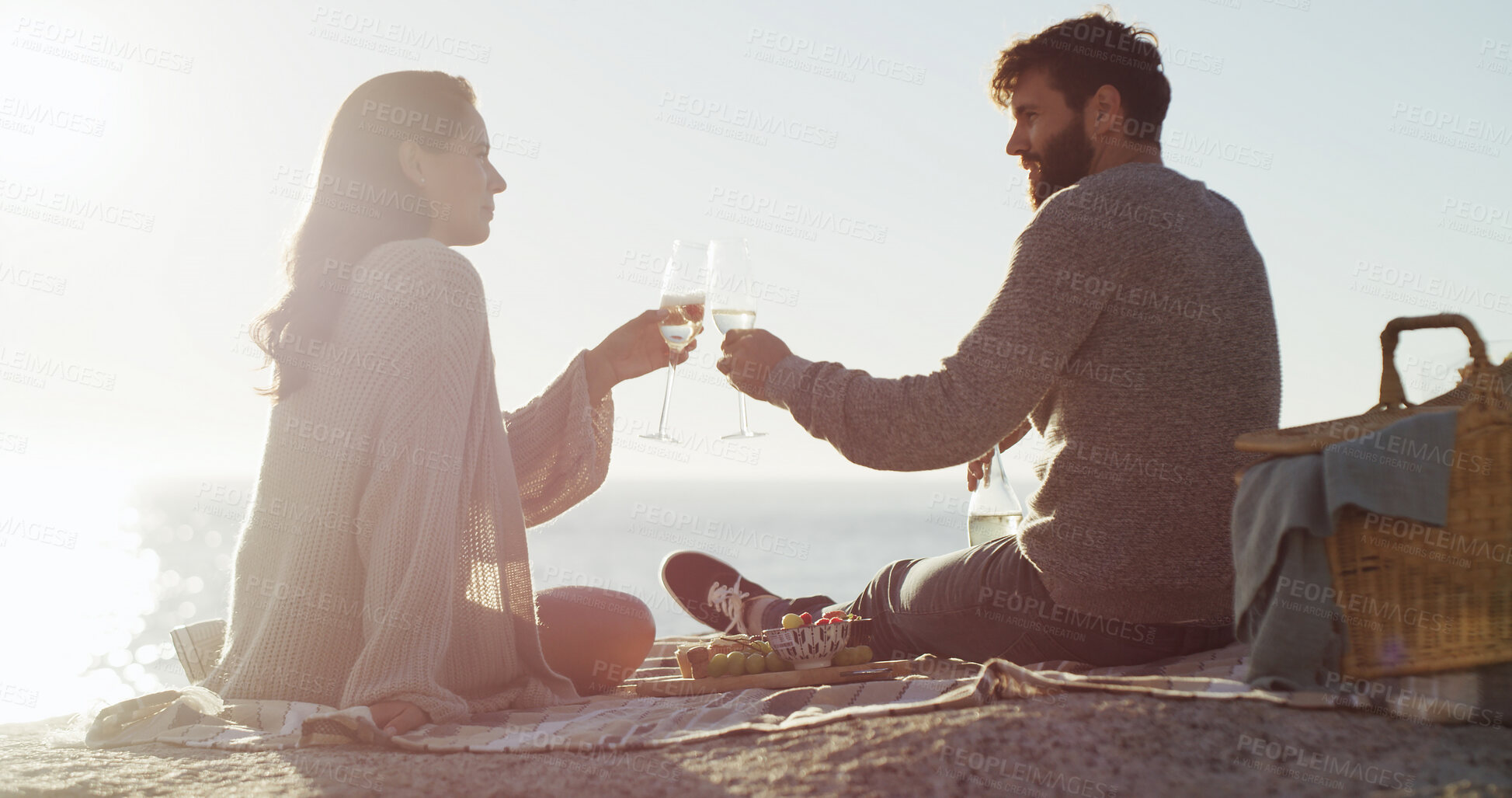 Buy stock photo Beach, picnic and couple with champagne, cheers and bonding together with vacation, relax and marriage. Ocean, alcohol and man with woman, anniversary and celebration with holiday, care and toast
