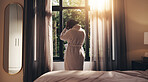 Woman, back view and morning with stress in home for mental health, depression or insomnia. Female person, anxiety or pain with sleep deprivation by window curtains in robe for loneliness in house