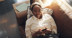 Black woman, happy and relax with phone in home for social media browsing, online news and streaming. Above, comfortable and person with smartphone on sofa for app download and scrolling dating site