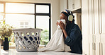 Smelling, fabric and woman with headphones, home or streaming song for chores, clean or fresh scent. Fragrance, black person and listen to music with tech, housework or basket with clothes in kitchen
