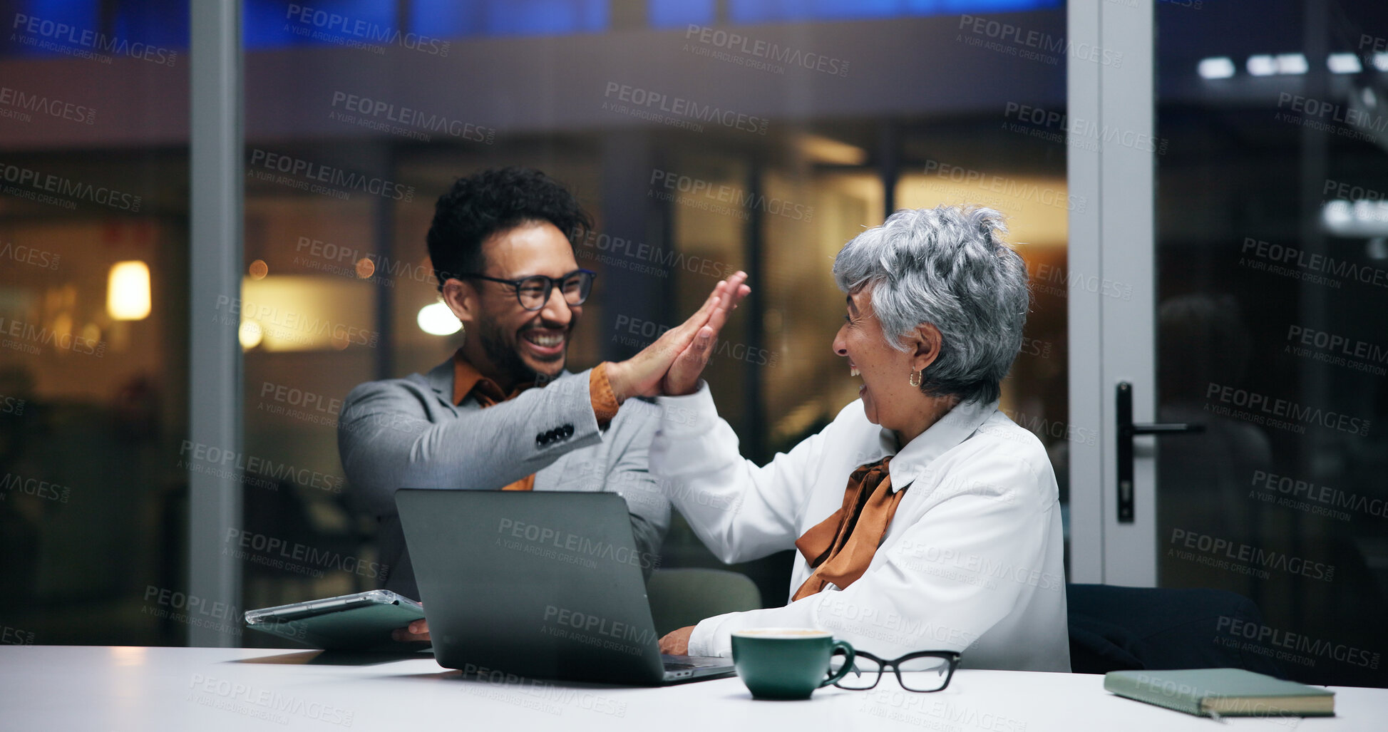 Buy stock photo Happy, business people or night with high five or laptop in office for winning, success or teamwork. Businessman, woman and employees with smile or technology for achievement or project deadline