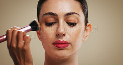 Buy stock photo Makeup artist, beauty and woman with brush in studio for foundation application, glow or aesthetic. Apply cosmetics, model and tools for powder, product and facial transformation on brown background