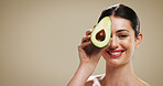 Portrait, woman and skincare with avocado, studio background or smile for facial treatment or beauty. Mockup space, hydration and person with fruit for smooth skin, natural cosmetics and dermatology