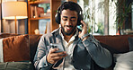 Happy, man and phone with headphones on sofa for streaming subscription, audio playlist or song. Smile, person and relax with smartphone in lounge for listening to radio and feel good album in home