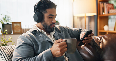 Buy stock photo Coffee, man and phone with headphones in home for music playlist, social media video or podcast. Online, person and relax with smartphone on sofa for listening to radio, album and audio subscription