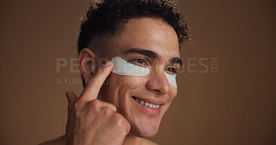 Buy stock photo Skincare, eye pads and man in studio for beauty, natural or grooming for facial routine. Happy, cosmetics and person with collagen patches for dermatology treatment by brown background with space.
