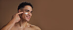 Skincare, face cream and man in studio for natural, beauty or facial routine with hydration or moisturizer. Happy, mockup space and person with sunscreen for dermatology treatment by brown background
