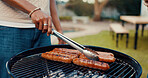 Hands, person and bbq food on grill for meal prep, grilled sausage and cooking for social gathering. Man, tongs and barbecue meat on heat for lunch, cookout event and party reunion in houses backyard