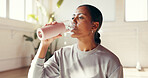 Woman, water and drinking with bottle in studio for hydration, recovery or natural sustainability. Female person, yogi or thirst with mineral liquid for fitness, rest or workout break in health club