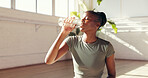 Black woman, drinking and water bottle in studio for hydration, recovery or natural sustainability. Female person, yogi or thirst with mineral liquid for fitness, rest or workout break in health club