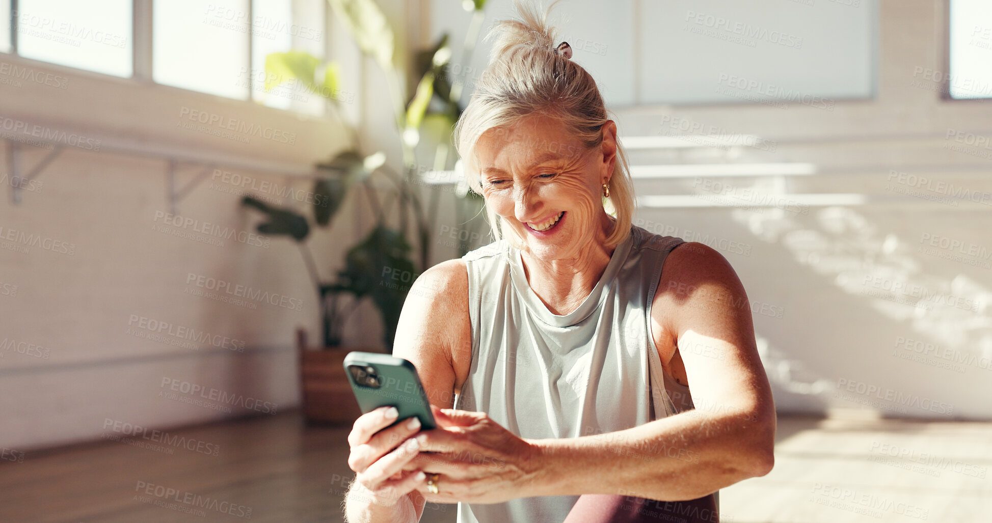 Buy stock photo Phone, smile and old woman in studio for fitness, exercise schedule or information online for health. Mobile, gym or happy senior person check wellness app for pilates, track progress or retirement