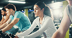 Spin class, fitness and woman with group in gym on bicycle for exercise, cardio workout and training. Sports center, cycling and people on stationary bike for endurance challenge, health and wellness