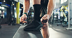 Man, hands and tying with shoes in gym for workout preparation or indoor exercise on bench. Closeup, male person or tie laces with sneakers or getting ready for fitness or training in health club