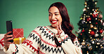 Christmas, smile and woman with selfie in studio for festive, tradition or holiday celebration. Happy, phone and person with photography picture for memory by xmas tree and gifts by green background.