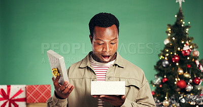 Buy stock photo Christmas, gift and shock with black man in studio for holiday season, celebration and xmas package. Present, festive tradition and surprise with person and box on green background for wow and omg