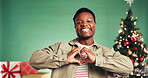 Christmas, heart hands and portrait of black man in studio for holiday celebration. Xmas, happy person and love sign for festive season, thank you or gift appreciation on green background with space