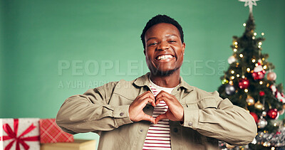 Buy stock photo Christmas, heart hands and portrait of black man in studio for holiday celebration. Xmas, happy person and love sign for festive season, thank you or gift appreciation on green background with space