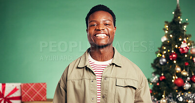 Buy stock photo Portrait, man and celebration of Christmas, studio and excited for Xmas season and green background. Black person, smile and tree with ornaments for December holiday, presents or happy in Nigeria
