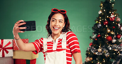 Buy stock photo Christmas, happy and woman with selfie in studio for festive, tradition or holiday celebration. Smile, influencer and person with photography picture by xmas tree and gifts by green background.