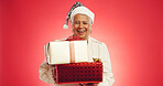 Christmas, senior woman or gift in studio with portrait, happy or giveaway box in retirement. Elderly person, excited or present on red background space for festive season, Xmas tradition or surprise