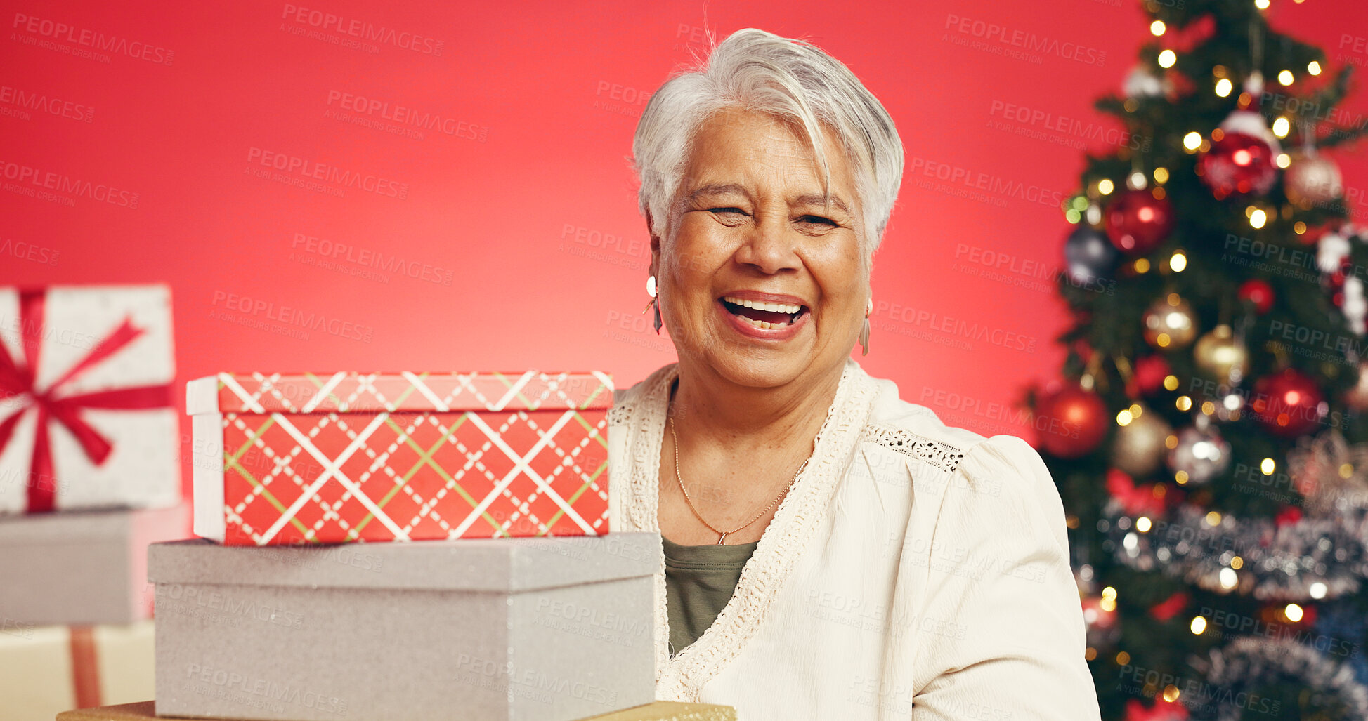 Buy stock photo Christmas, senior woman and present in studio for holiday tradition, giveaway prize or retirement. Portrait, old person or gift box on red background for xmas promotion, festive season or celebration