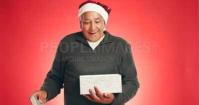 Buy stock photo Christmas, gift and mature man in studio with surprise for festive event, tradition and celebration. Space, happy and person with box on red background for holiday, December vacation and xmas present