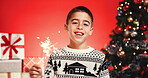 Portrait, child and boy with sparkler, Christmas or celebration for festive season or red background. Studio, happy and excited for December holiday, presents and decorations for Xmas and event