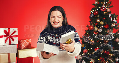 Buy stock photo Portrait, woman and gift in studio for Christmas holiday, surprise box and festive celebration. Smile, female person or package for xmas present, giveaway reward and tradition prize on red background