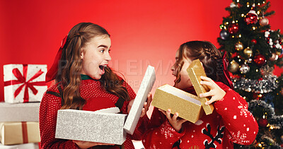 Buy stock photo Surprise, children and gift in studio for Christmas holiday, family wishlist and festive celebration. Excited, kids and open package for xmas present, tradition and bonding together on red background