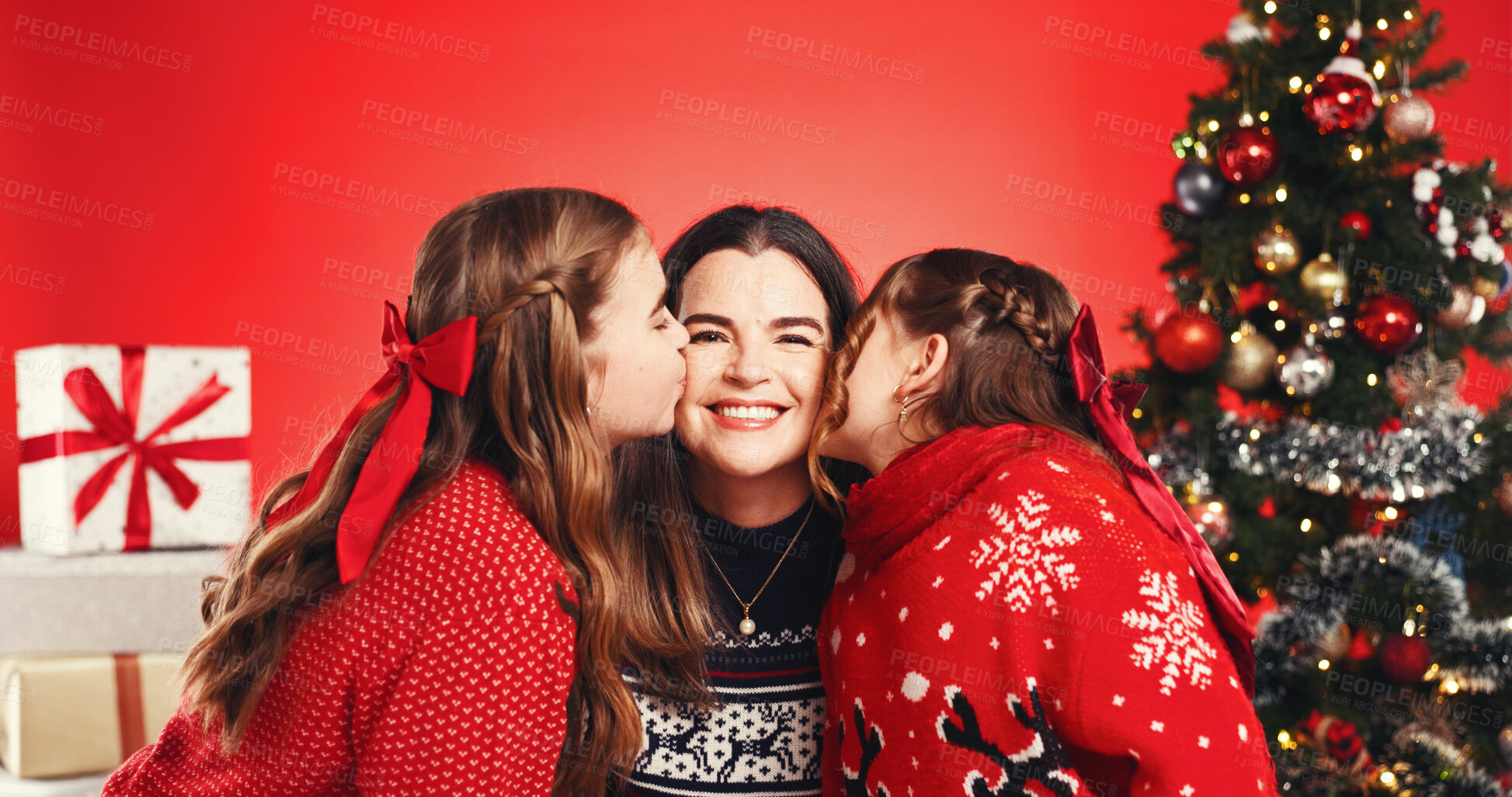 Buy stock photo Christmas, studio and mom with children, kiss or excited for December holiday, portrait and bonding. Red background, woman and happy with girls, love and kids with affection on Xmas season or tree