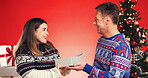 Smile, couple and gift in studio for Christmas holiday, surprise box and festive celebration. People, love and package with partner for xmas present, tradition and bonding together on red background