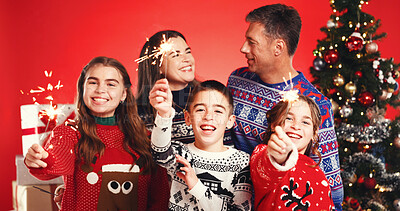 Buy stock photo Happy, christmas and family with sparklers in studio with tradition, festive or holiday celebration. Smile, bonding and portrait of children with parents for xmas season together by red background.