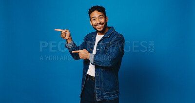 Buy stock photo Happy man, portrait and pointing with space in studio for advertising or pick on a blue background. Male person, model or marketing with smile, gesture or showing list for option, selection or choice