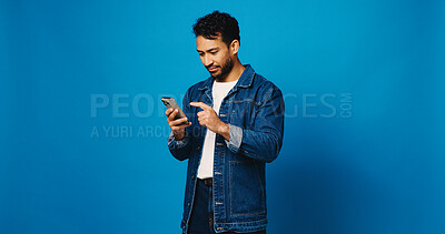 Buy stock photo Phone, chat and scroll with man in studio for social media, networking and connection. Mockup space, text message and search with person on blue background for contact, typing or communication app