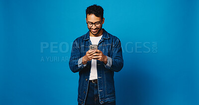 Buy stock photo Reading, phone and glasses with man in studio for social media, communication and blog post. Online news feed, text message and networking chat with person on blue background for mockup space and app