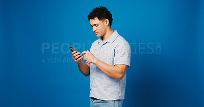 Buy stock photo Reading, phone and scroll with man in studio for social media, communication and blog post. Online news feed, text message and networking chat with person on blue background for space and app