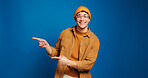 Happy man, portrait and pointing with fashion in studio for advertising on a blue background. Male person, model or marketing with smile, gesture or selection for choice or option on mockup space