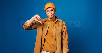 Buy stock photo Man, sad and portrait with thumbs down in studio for bad news, university rejection or disappointed. Mockup space, college student and hand gesture for negative feedback or decline on blue background
