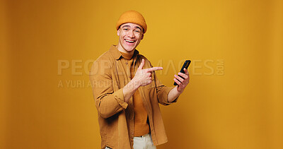 Buy stock photo Pointing, phone and portrait of man in studio for online notification, website and communication. Mockup, space and person with gesture, shocked and happy on smartphone for social media, post or news