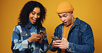 Phone, excited and couple in studio with networking, communication or chatting on mobile app. Happy, tech and man with woman on cellphone for contact on social media together by yellow background.