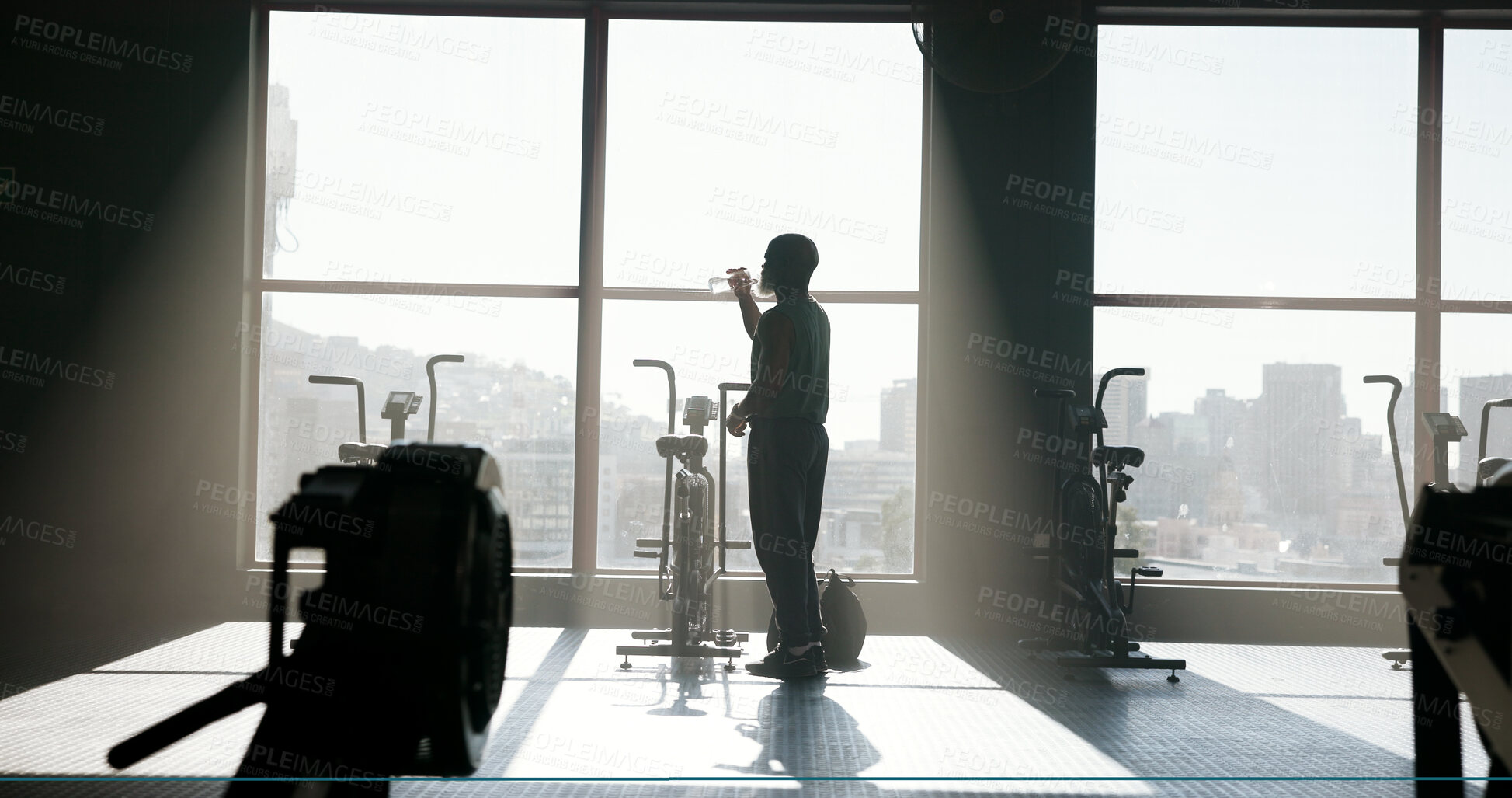 Buy stock photo Fitness, mature man or drinking water at gym for hydration, workout recovery or nutrition. Sunlight, window or back of athlete at sports club with liquid refresh for exercise break, thirsty or health