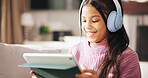 Tablet, headphones and happy child on sofa online for elearning, educational games and internet. Relax, weekend and girl on digital tech for watching videos, streaming movies and subscription in home