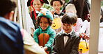 Children, group and sweets at door on halloween for tradition, costume and trick or treat. Holiday, neighborhood kids and happy with man at house for candy collection, fantasy dress up or celebration