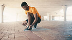 Black man, tying laces and shoes for running, fitness or cardio health in city with start or ready outdoor. Male runner, prepare sneakers or footwear for training, workout or exercise in urban town